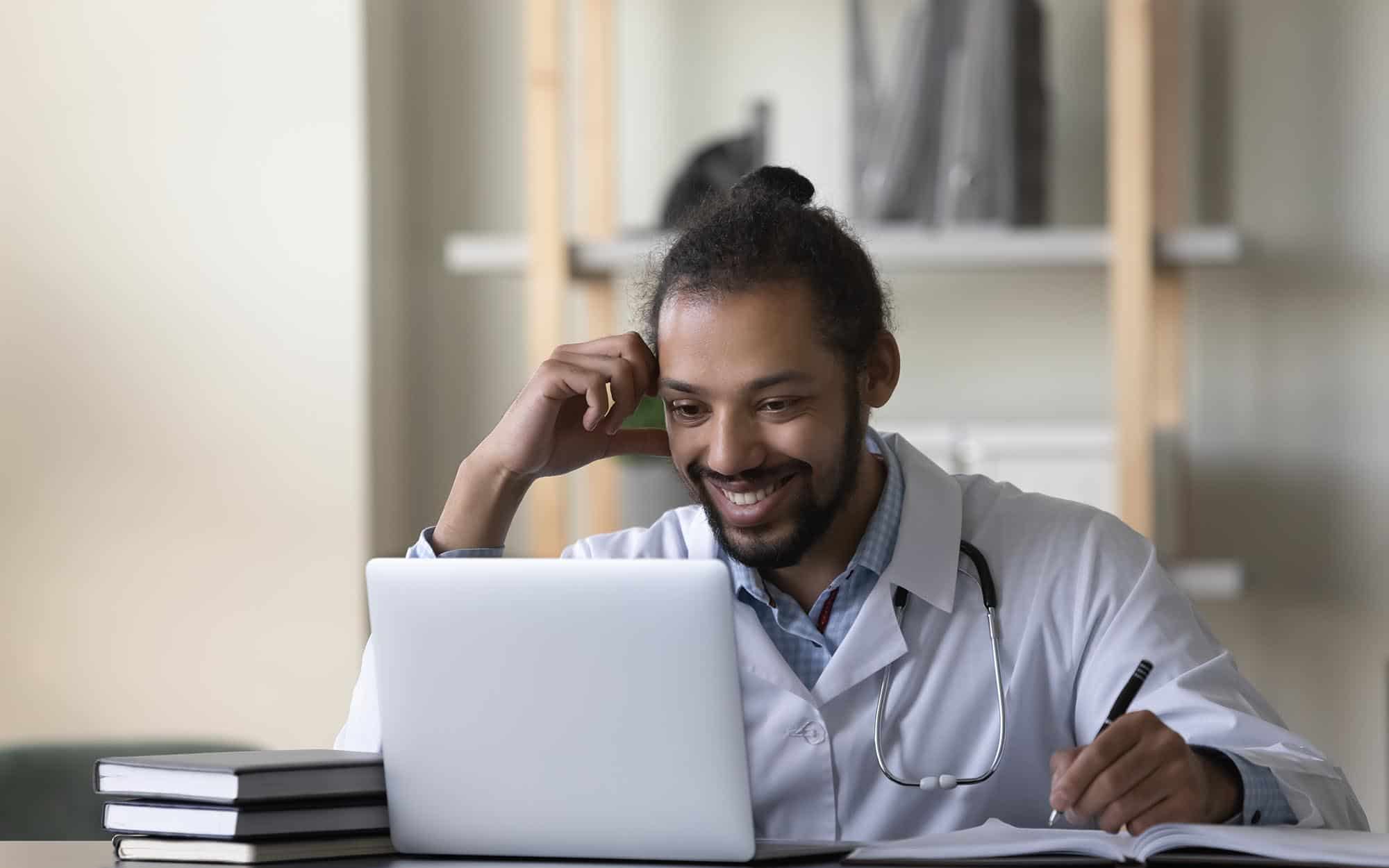 Front view of a doctor smiling at a laptop screen