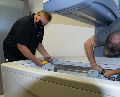 Side view of two men working on DXA machine