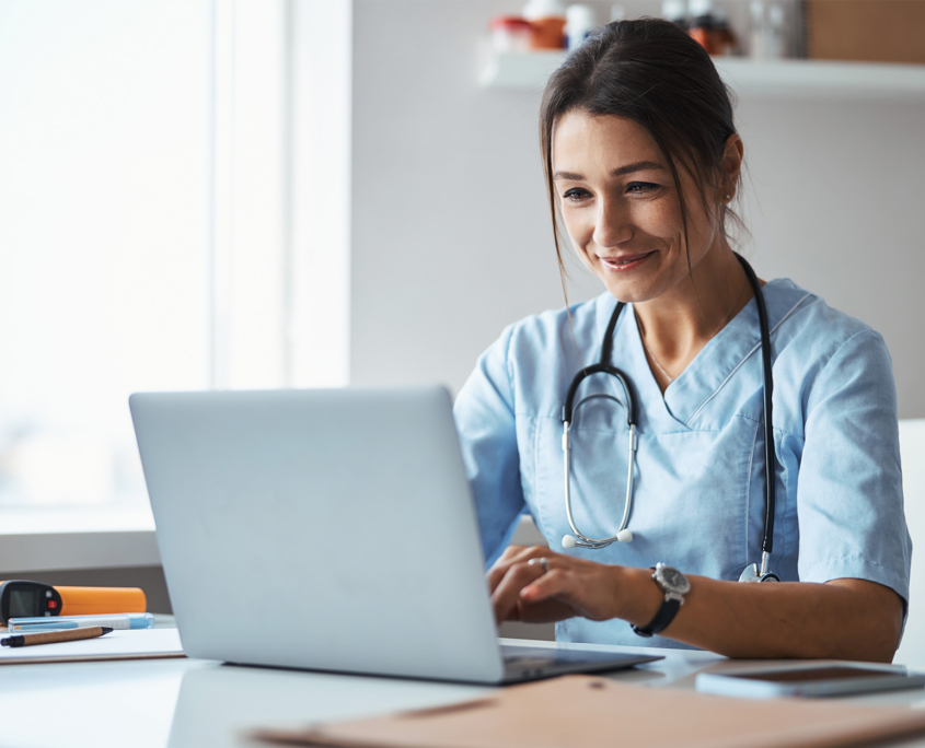 Joyful female doctor using laptop in clinic