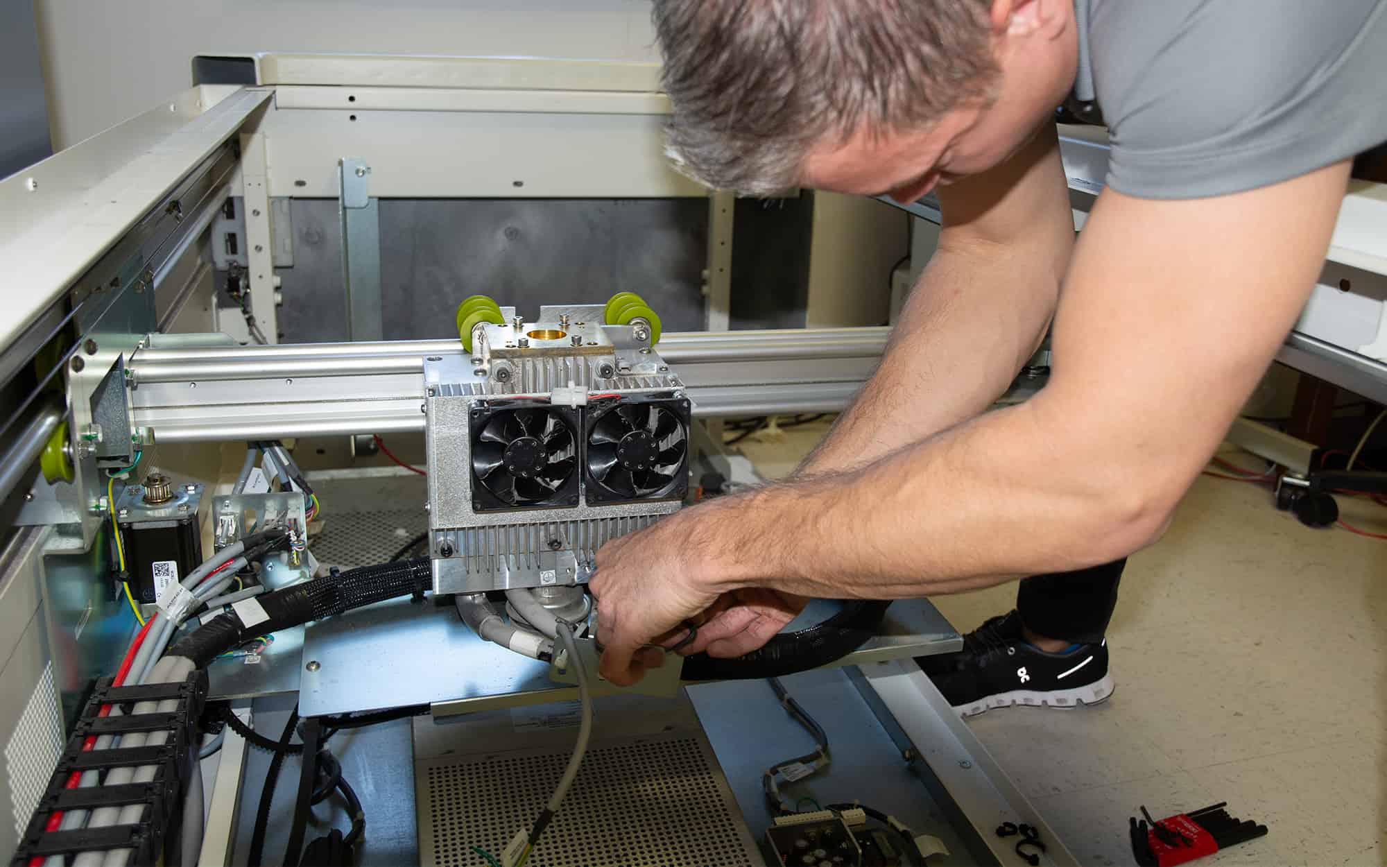 Side view of a DEXA specialist working on the internals of a DXA machine